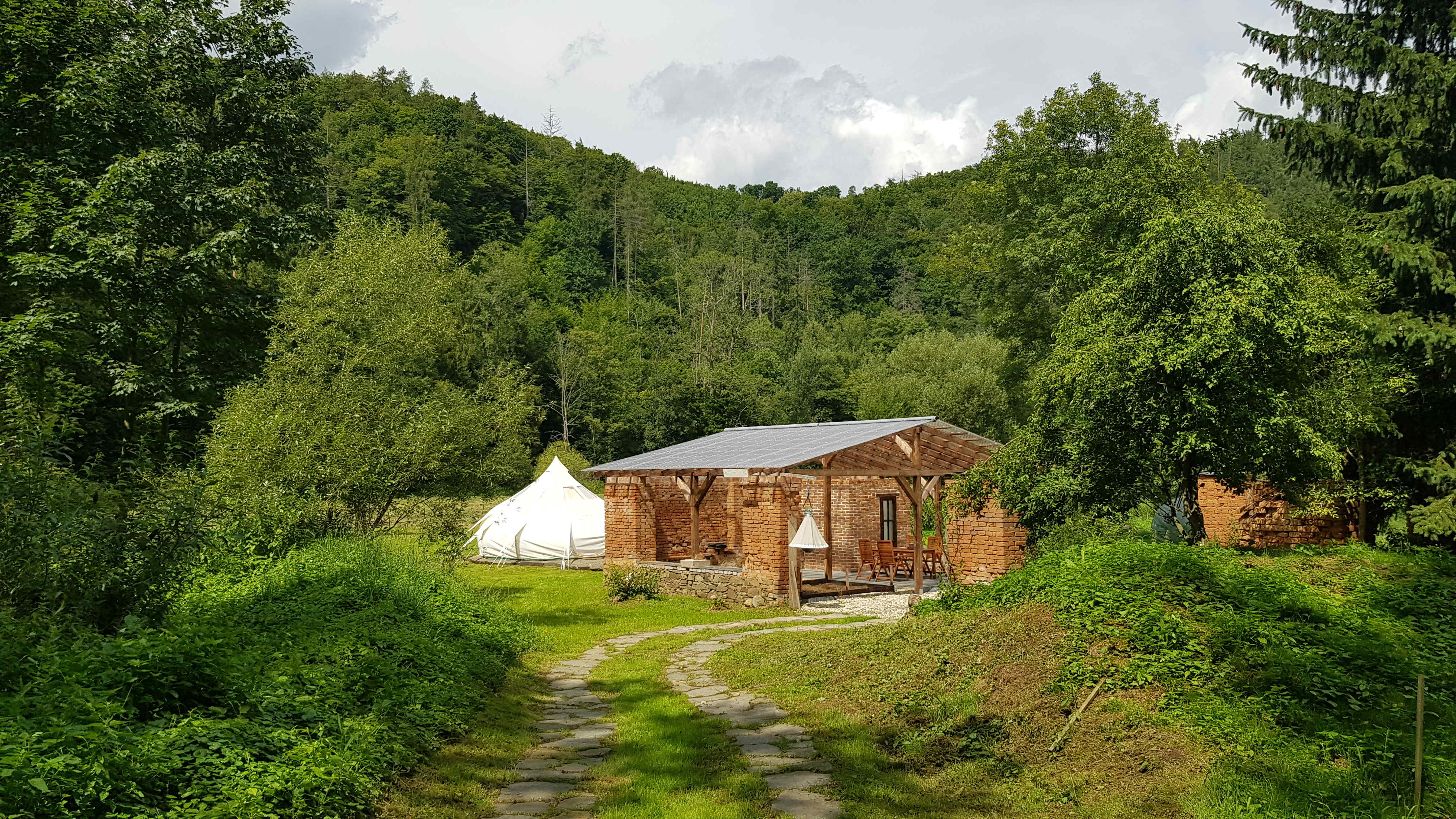 Luxurious glamping tent amidst flamboyant greenery behind old water mill